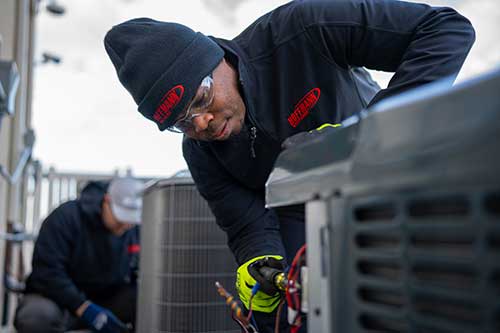 student learning HVAC repair in the field