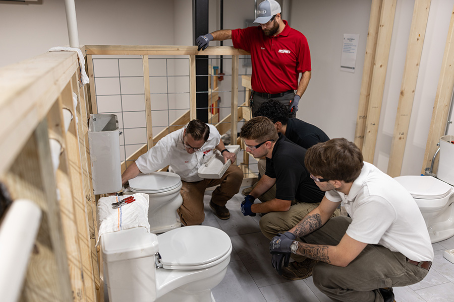 instructor showing students how to fix a toilet